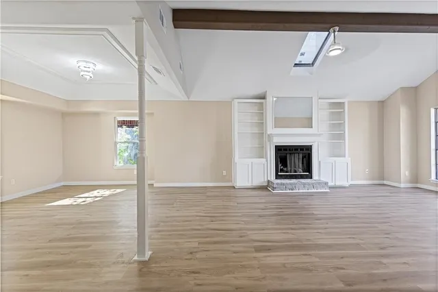 a view of an empty room with wooden floor fireplace and a window