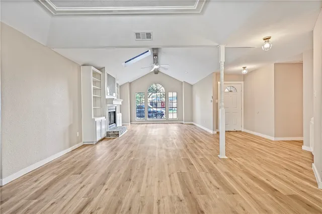 a view of a big room with wooden floor fireplace and windows