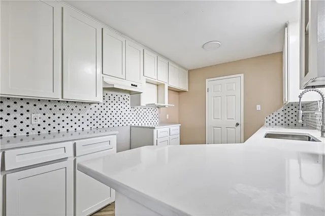 a kitchen with white cabinets and sink