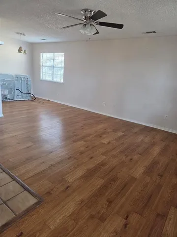 an empty room with wooden floor fan and windows