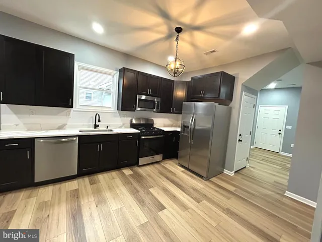 a large kitchen with stainless steel appliances kitchen island granite countertop a refrigerator and a stove top oven