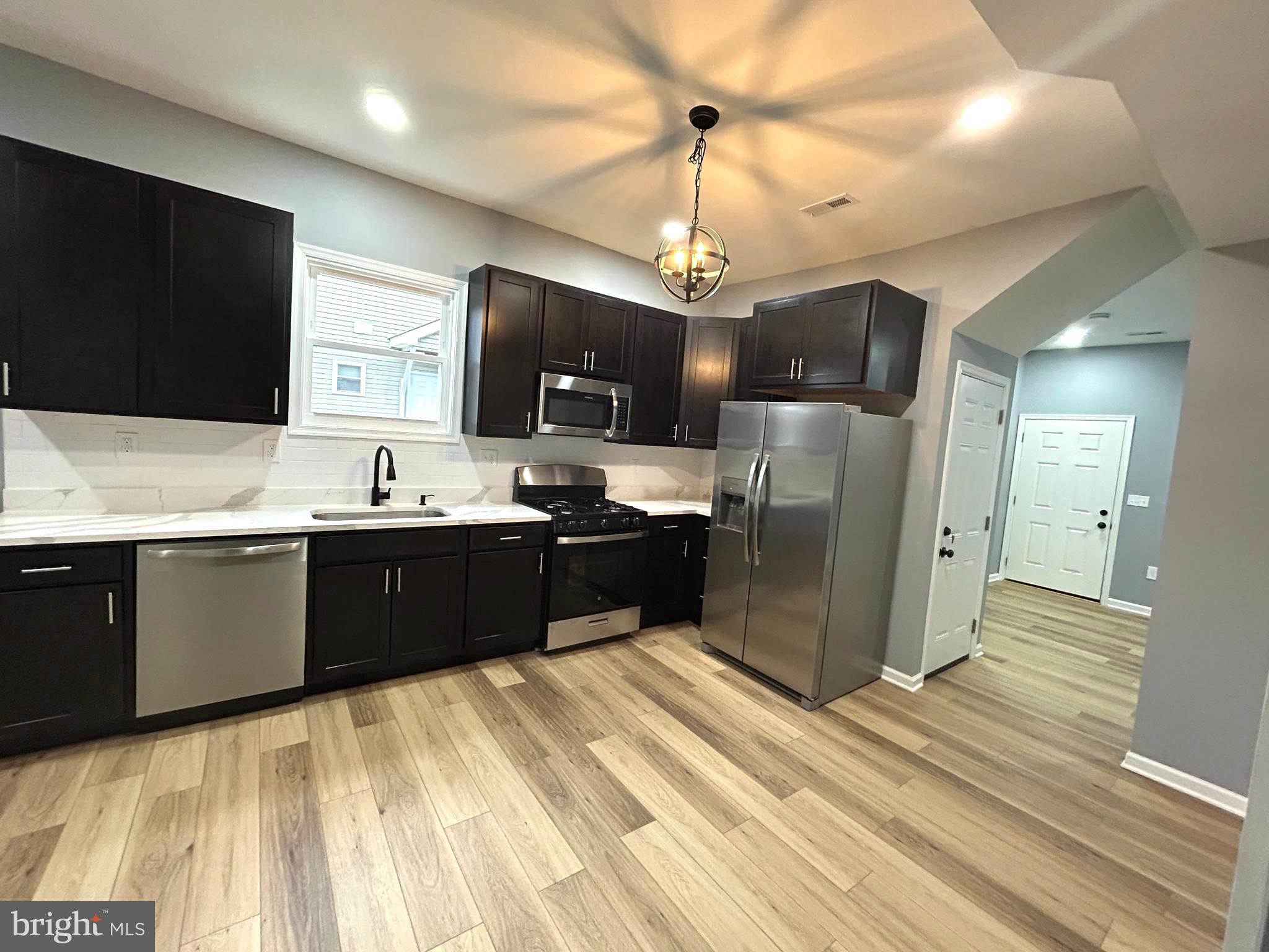 3902 West Rogers Avenue, Unit 1 Baltimore, MD 21215 - Photo 10 of 12 a large kitchen with stainless steel appliances kitchen island granite countertop a refrigerator and a stove top oven