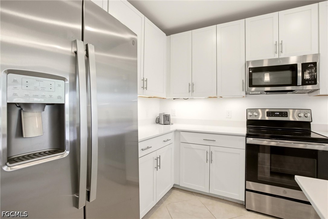 3751 Pebblebrook Ridge Court, Unit 101 Fort Myers, FL 33905 - Photo 9 of 48 a kitchen with white cabinets and stainless steel appliances