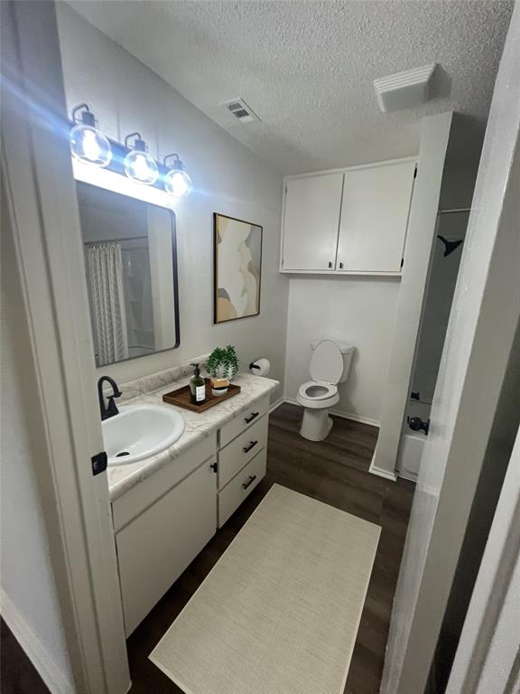 4639 Williams Road, Unit 118 Benbrook, TX 76116 - Photo 7 of 13 Full bath featuring a textured ceiling, vanity, wood finished floors, and a shower with shower curtain