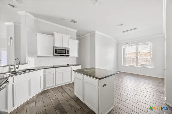 a kitchen with granite countertop cabinets stainless steel appliances a sink and a window