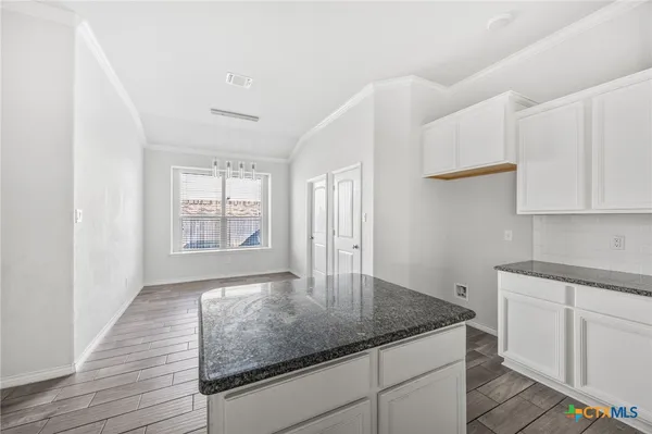 a kitchen with granite countertop white cabinets and a window