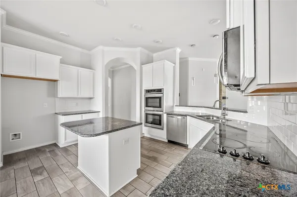 a kitchen with granite countertop a sink a counter top space and cabinets