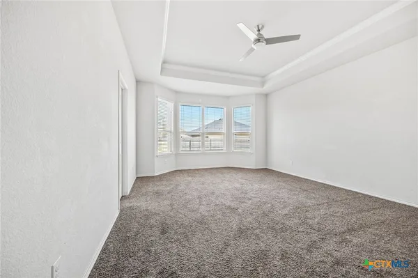 an empty room with windows and fan