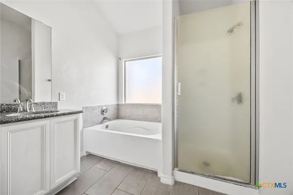 a bathroom with a granite countertop sink a mirror and a bathtub