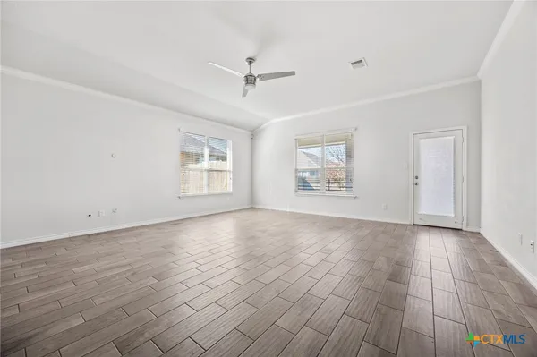 a view of an empty room with a window and wooden floor