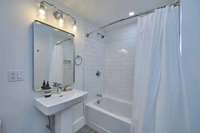 a bathroom with a sink a mirror a bathtub and shower