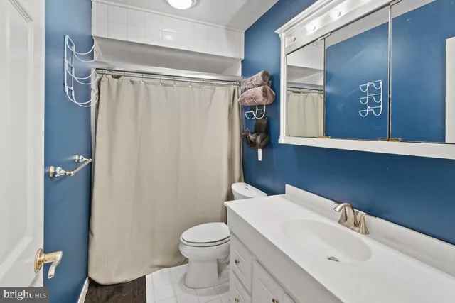 a bedroom with a bed a standing fan and a bookshelf