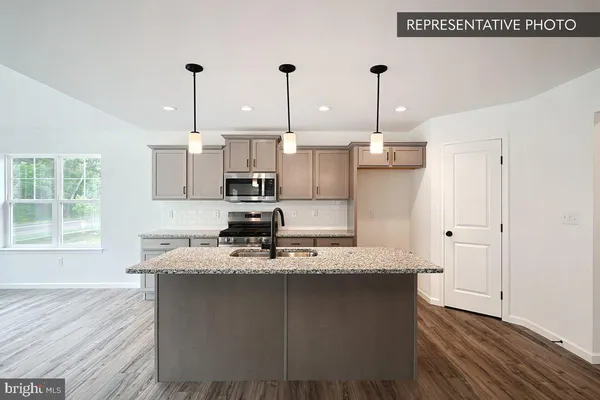 a kitchen with kitchen island stainless steel appliances sink refrigerator and wooden floor
