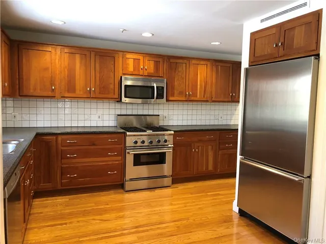 an empty room with wooden floor fireplace and windows