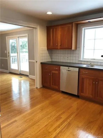 a view of an empty room with wooden floor fireplace and a window