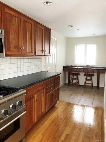 a view of a hallway with wooden floor and a kitchen