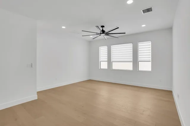 an empty room with windows and ceiling fan