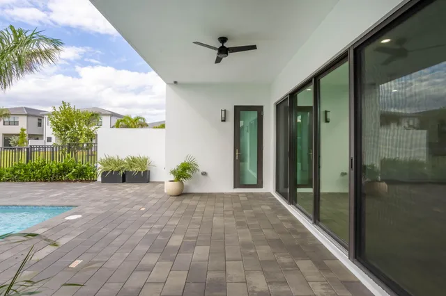 an empty room with chandelier fan and windows