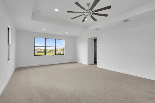 an empty room with windows and ceiling fan