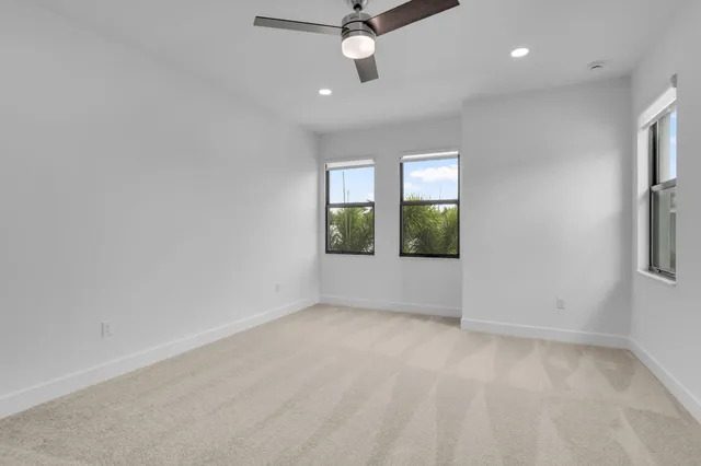 an empty room with windows and ceiling fan