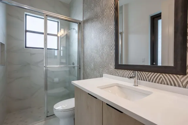 a bathroom with a shower sink vanity mirror and toilet
