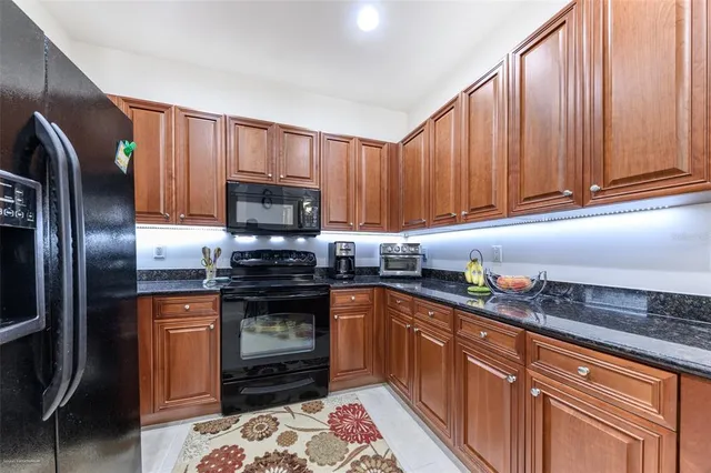 a kitchen with granite countertop a refrigerator stove and microwave