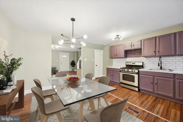 a kitchen with stainless steel appliances granite countertop a stove top oven a sink dishwasher and a dining table with wooden floor