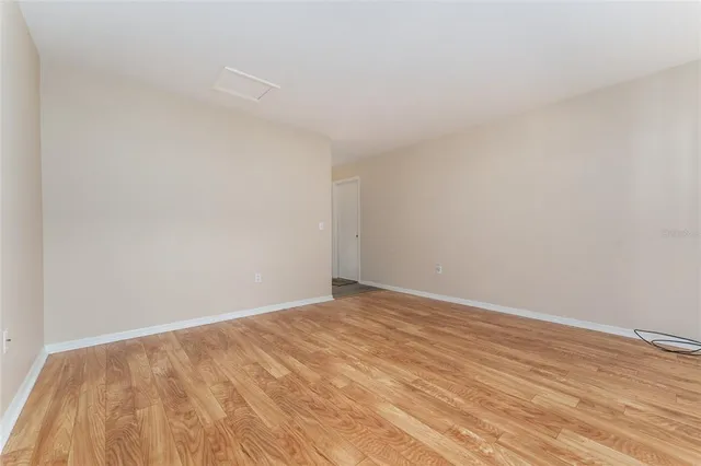 an empty room with wooden floor chandelier fan and windows