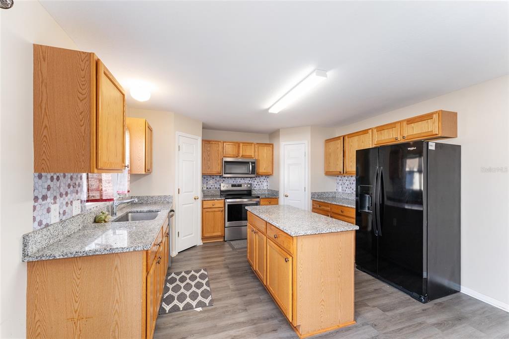 2661 Northeast 42nd Road Ocala, FL 34470 - Photo 26 of 74 a kitchen with granite countertop kitchen island stainless steel appliances a refrigerator a sink a stove a counter top space and cabinets