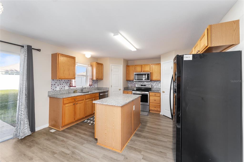 2661 Northeast 42nd Road Ocala, FL 34470 - Photo 28 of 74 a kitchen with stainless steel appliances granite countertop a refrigerator a sink dishwasher a stove with wooden cabinets and wooden floor