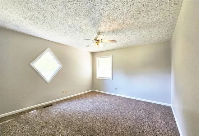 an empty room with a window and a ceiling fan