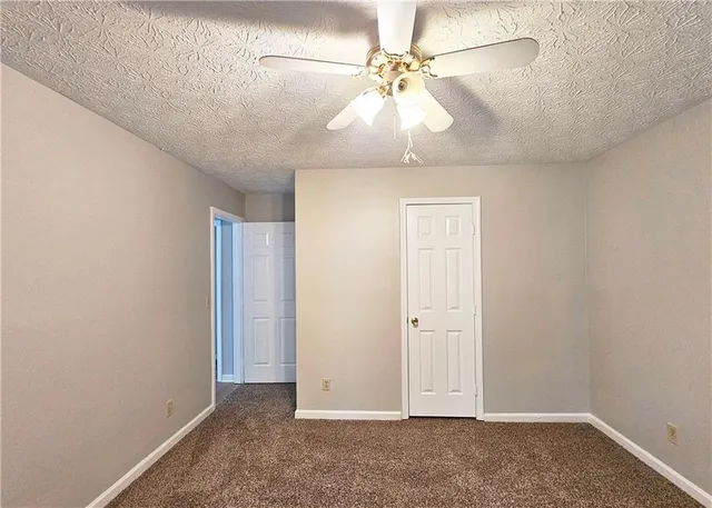 an empty room with a chandelier fan and windows