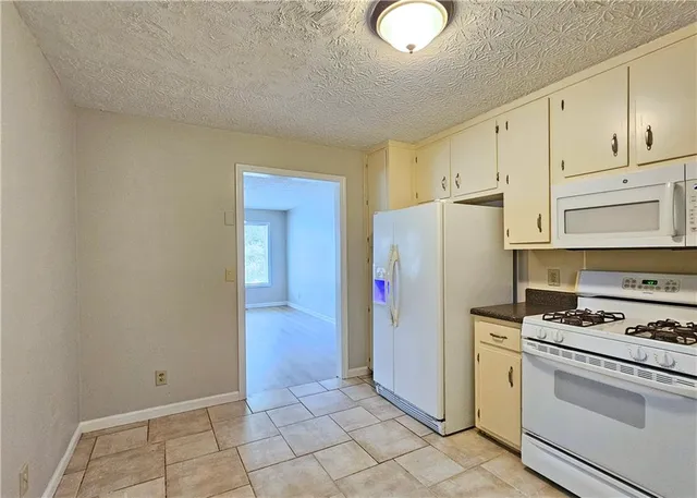 a kitchen with granite countertop a refrigerator stove and white cabinets