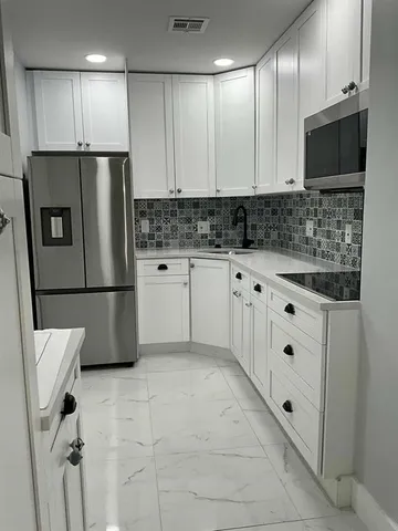 a kitchen with stainless steel appliances a refrigerator sink and microwave