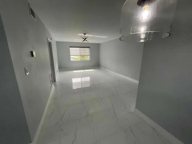 en empty room with windows and brick wall