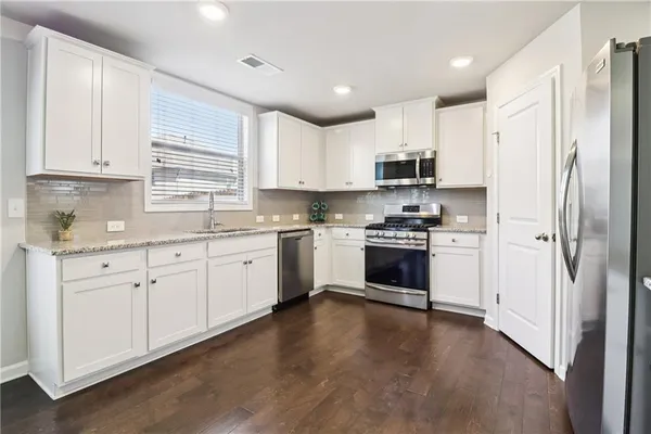 a kitchen with granite countertop white cabinets and stainless steel appliances