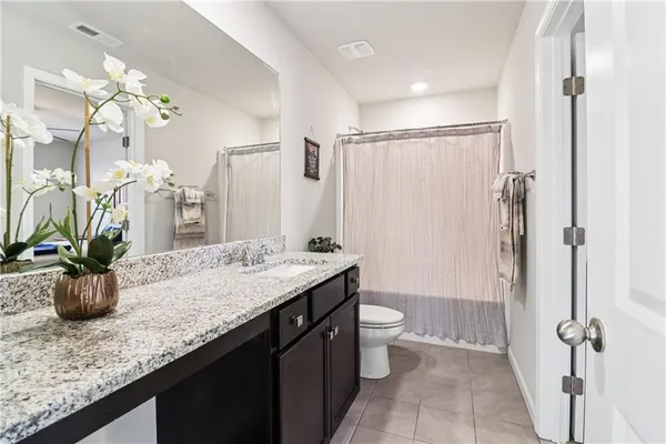a bathroom with a granite countertop sink a toilet a mirror and shower