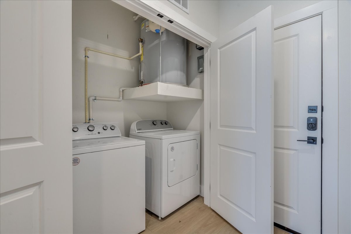 3000 Duval Street, Unit 102 Austin, TX 78705 - Photo 21 of 40 Laundry area featuring water heater, light wood-style floors, and washing machine and clothes dryer
