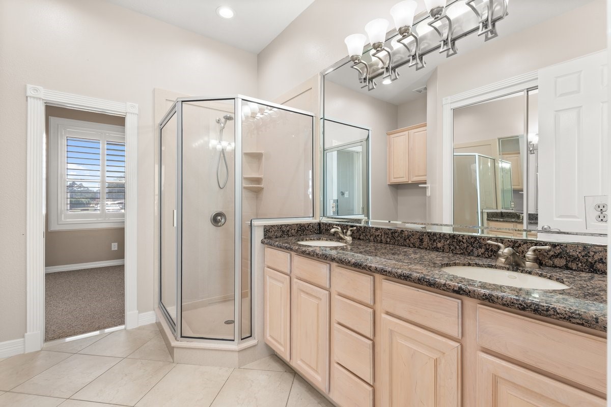 168 Lake Point Boulevard, Unit C102 Conroe, TX 77356 - Photo 20 of 35 This bathroom features a spacious double vanity with granite countertops, a glass-enclosed shower, ample lighting, and neutral tile flooring. A window provides natural light, enhancing the bright and open feel.