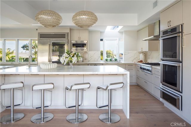 a kitchen with granite countertop a counter space cabinets stainless steel appliances and a chandelier