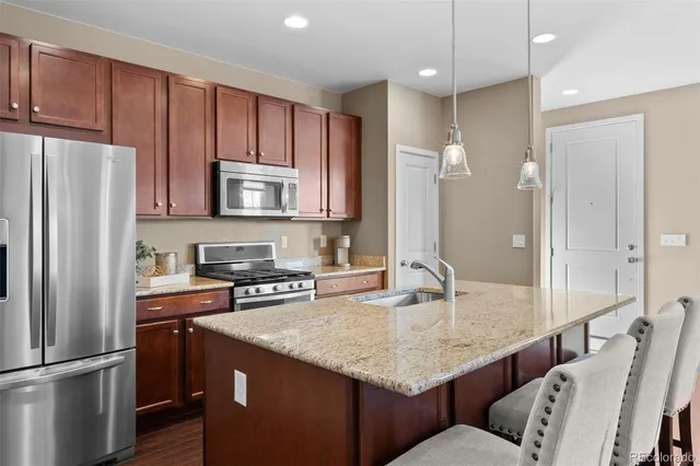 a kitchen with stainless steel appliances granite countertop a kitchen island a stove a refrigerator a sink and a cabinets