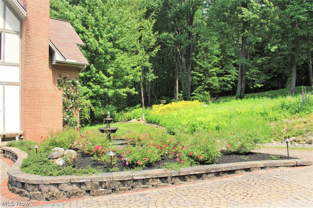 6491 Dewey Road Thompson, OH 44086 - Photo 30 of 35 Rose garden with a fountain, fern garden, brick paver driveway, and capped stone wall.