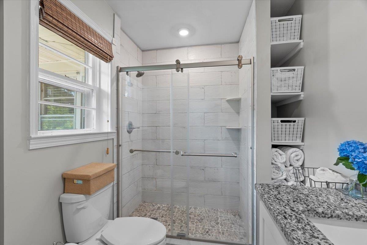4491 Garnett Road Memphis, TN 38117 - Photo 17 of 32 Shower enclosure with sliding glass door, pebble floor, and tiled walls