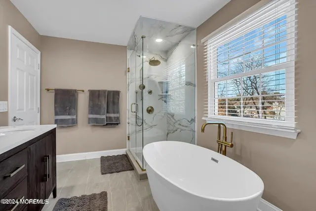 a bathroom with a large tub a sink a window and a shower