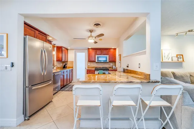 a kitchen with granite countertop a refrigerator a stove top oven a dining table and chairs