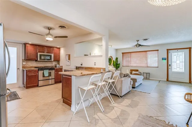 a open kitchen with stainless steel appliances granite countertop a stove top oven a sink dishwasher a dining table and chairs with wooden floor