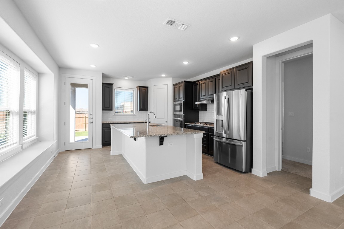 121 Rangel Drive Liberty Hill, TX 78642 - Photo 6 of 23 a large kitchen with stainless steel appliances kitchen island a large counter top and a refrigerator