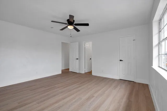 a view of empty room with wooden floor and fan
