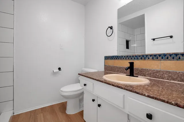 a bathroom with a granite countertop sink a toilet and a mirror