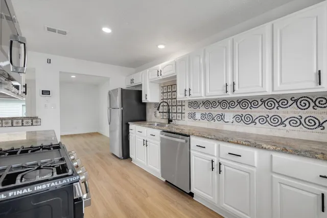 a kitchen with granite countertop a sink stove and refrigerator